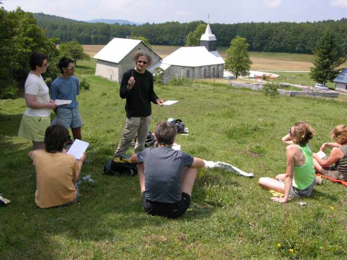 Personnes assies dans l'herbe au milieu des montagnes